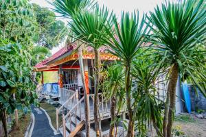 una casa con palme di fronte di Lotus Garden Huts a Nusa Lembongan