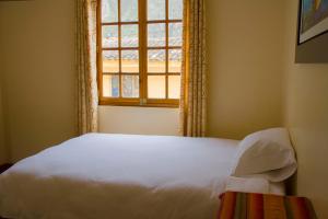 1 dormitorio con cama blanca y ventana en Tumy house B&B, en Ollantaytambo