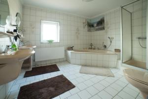 a bathroom with a tub and a shower and a sink at Gästehaus Marichen in Aurich