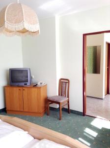 a room with a tv and a chair and a mirror at Hotel Garni in Bad Schallerbach