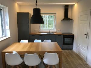 a kitchen with a wooden table and white chairs at The Place by Baltic sea in Łukęcin