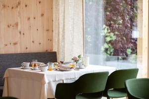 una mesa con mantel blanco y sillas verdes en Ladurner, en Lagundo