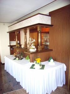 een lange witte tafel met bloemen op een kamer bij Gaststätte & Pension Jiedlitz in Burkau