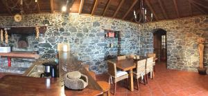 Cette chambre est dotée d'une table, de chaises et d'un mur en pierre. dans l'établissement Casa dos Reis, à Calheta