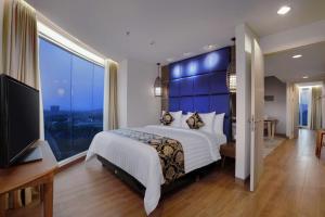 1 dormitorio con cama grande y ventana grande en The Alana Hotel and Conference Sentul City by ASTON, en Bogor