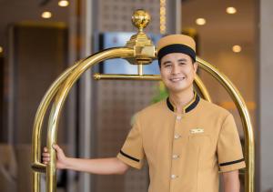 um homem de uniforme ao lado de um chuveiro dourado em Muong Thanh Luxury Vientiane Hotel em Vientiane