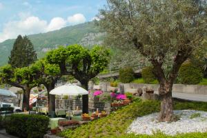 un groupe d'arbres avec des tables et un parapluie dans l'établissement Il Grifo, à Lenno