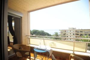 een balkon met een tafel en stoelen en een groot raam bij T2 Terrasse Vue Mer - Route des Sanguinaires in Ajaccio