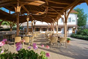 a patio with tables and chairs under a wooden pavilion at Babiččina Zahrada Penzion & Restaurant in Pruhonice