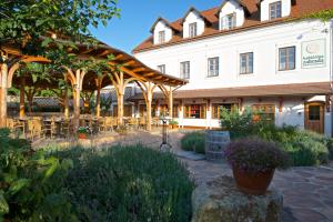 a large white building with a patio with tables and chairs at Babiččina Zahrada Penzion & Restaurant in Pruhonice