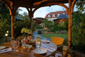 a wooden table in a gazebo with a house at Babiččina Zahrada Penzion & Restaurant in Pruhonice