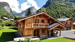 ein Blockhaus mit Bergen im Hintergrund in der Unterkunft Chalet Luxe Les Mélèzes in Samoëns