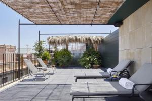 eine Terrasse mit Liegen und Stühlen auf einem Gebäude in der Unterkunft Casa Camper Barcelona in Barcelona