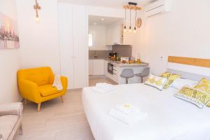 um quarto com uma cama branca e uma cadeira amarela em Rambla de Marisol Apartments em Castelldefels