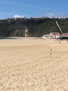 une plage de sable avec un pôle rouge dans le sable dans l'établissement Grace Beach House, à Nazaré