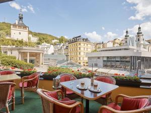 um pátio com mesas e cadeiras e vista para a cidade em Hotel Romance em Karlovy Vary