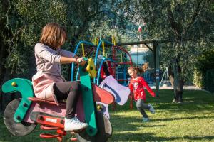 Eine Frau und ein Kind spielen auf einem Spielplatz in der Unterkunft Hotel Riviera Panoramic Green Resort in Limone sul Garda