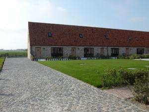 ein Backsteingebäude mit einem Rasenplatz davor in der Unterkunft vakantiehoeve 't Goed ter Leeuwen in De Haan