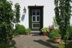 une porte verte sur une maison blanche avec des plantes en pot dans l'établissement Feldmann-Schütte, à Schmallenberg