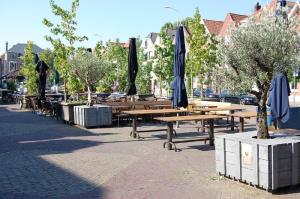 una fila de mesas de madera con sombrillas en una calle en Hotel La Reine, en Eindhoven