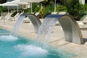 uma fonte de água numa piscina com mesas e guarda-sóis em Hotel Orient & Pacific em Lido di Jesolo