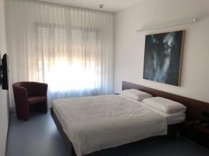 a bedroom with a bed and a window and a chair at Hotel Ceresio in Lugano