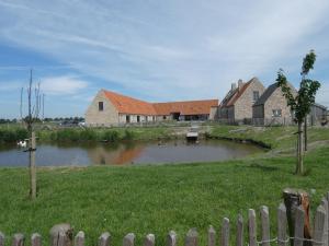 ein Haus mit einem Teich inmitten eines Feldes in der Unterkunft vakantiehoeve 't Goed ter Leeuwen in De Haan