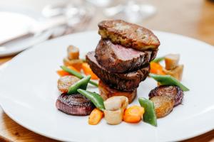 une assiette de denrées alimentaires contenant de la viande et des légumes sur une table dans l'établissement Van der Valk Hotel Apeldoorn - de Cantharel, à Apeldoorn