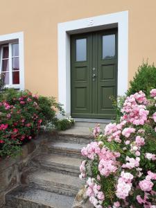 una puerta verde en una casa con flores rosas en Ferienwohnung am Spreeradweg in Bautzen, en Bautzen