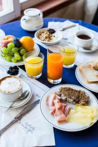 uma mesa azul com pratos de comida e copos de sumo de laranja em Hotel Sabrina em Castiglione della Pescaia