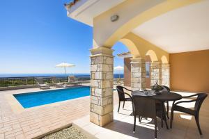 un patio con mesa y sillas y una piscina en Club St. George, en Pafos