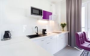 - une cuisine blanche avec évier et chaise violette dans l'établissement Apartamenty Vola Residence, à Varsovie