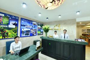 河内Hanoi Amorita Boutique Hotel & Travel的三个人站在一个笔记本电脑柜台上