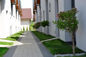 une passerelle entre deux bâtiments blancs avec des plantes à fleurs dans l'établissement Jastrzębia Marina - komfortowe całoroczne domki, à Jastrzębia Góra