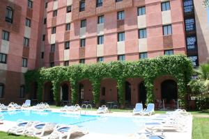 een groot gebouw met stoelen en een zwembad bij Hotel Relax Marrakech in Marrakesh