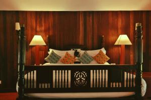 een zwart bed met kussens en 2 lampen bij Spice Village Thekkady - a CGH Earth Experience in Thekkady