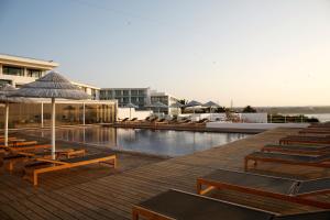 una piscina con sedie e ombrelloni accanto al resort di Memmo Baleeira - Design Hotels a Sagres