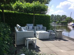 eine Terrasse mit Sofas und Tischen neben einem Wasserkörper in der Unterkunft Villa Envie in Terherne