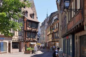 pessoas andando por uma rua em uma cidade com edifícios em Les Suites Du Cygne em Colmar