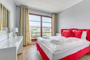 een slaapkamer met een rood en wit bed en een raam bij GRANO APARTMENTS Gdańsk Nowa Motława SPA & Wellness in Gdańsk