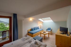 a room with two beds and a television and a couch at Hotel Dolomiten in Monguelfo