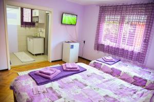 - une chambre violette avec 2 lits et des serviettes dans l'établissement PRENOĆIŠTE PILOT, à Niš