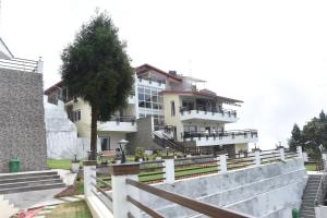 een wit gebouw met een boom ervoor bij Nirvana Retreat in Kurseong