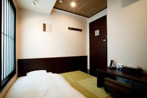 1 dormitorio con cama, escritorio y ventana en Ochanomizu Hotel Shoryukan, en Tokio