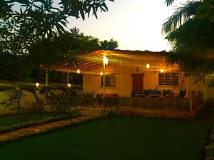 une petite maison avec terrasse couverte la nuit dans l'établissement West Valley Farm Villa, à Lavasa