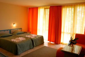 um quarto com 2 camas e cortinas vermelhas em Hotel Iskar & Aquapark - All Inclusive em Sunny Beach