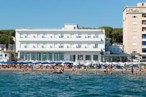 een groep mensen op een strand in het water bij Hotel Parrini in Follonica