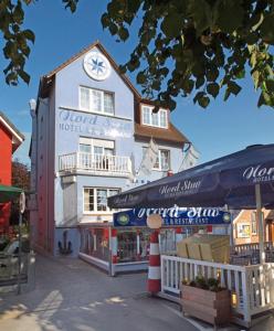 ein weißes Gebäude mit einer Uhr darüber in der Unterkunft Hotel-Restaurant Nord-Stuv in Cuxhaven