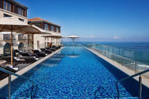 una piscina con sillas y sombrillas y el océano en The Setai Tel Aviv, a Member of the leading hotels of the world, en Tel Aviv