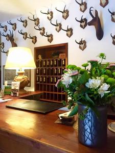 una mesa con un jarrón de flores y cabezas de ciervo en una pared en Hotel Dei Camosci, en Courmayeur